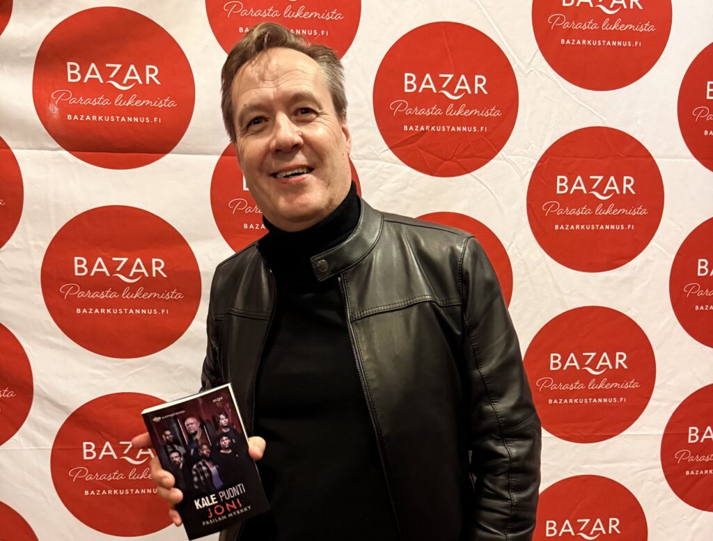 Dekkarikirjailija Kale Puonti pitää kädessään Joni-teostaan Pasilan Myrkyn kakkoskauden ennakonäytöksessä.